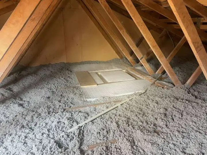 Grey cellulose insulation evenly covering a roof space around a manhole access.
