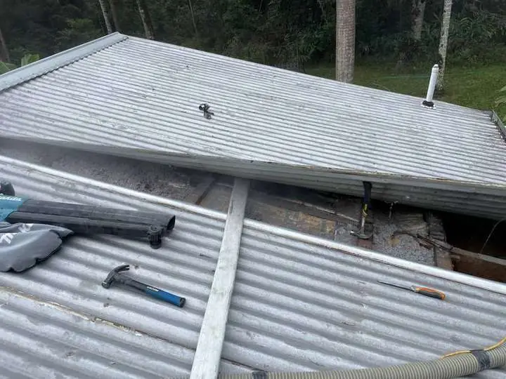 Corrugated roof section opened for insulation access on a raked roof.