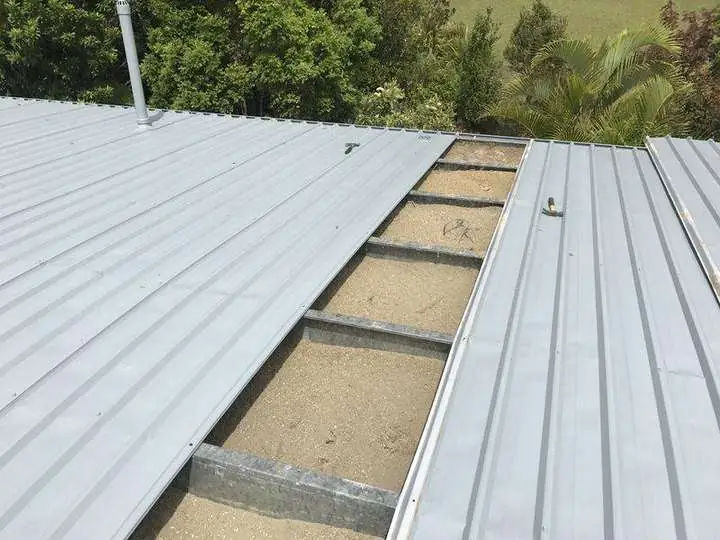 Metal roof sheets opened to show insulation coverage below the roof line.